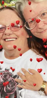 Two smiling people with glasses surrounded by red hearts.