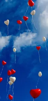 Red and white heart balloons floating in a blue sky.