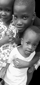 Black and white wallpaper of three smiling children.