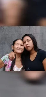 Mother and daughter embracing with gray background.