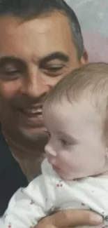 Father smiling warmly while holding baby.