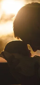 Silhouette of a father and child against a warm sunset background.