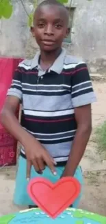 Young boy standing outdoors with a heart shape decoration.