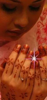 Intricate henna art on folded hands in pink tones.