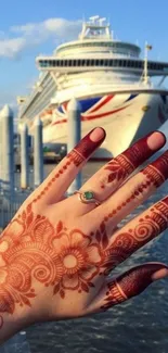 Hand with henna design against a cruise ship under clear sky.