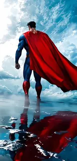Superhero stands with red cape in cloudy sky reflection.