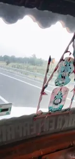 Highway view through a truck window with scenic, colorful elements and road ahead.