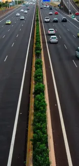 Aerial view of a bustling highway with cars and nature divider.