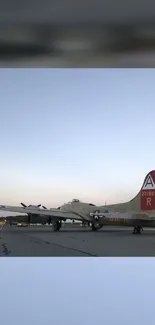 Historic airplane on runway at sunset with a clear sky.