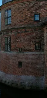 Brick castle wall by a calm water view.