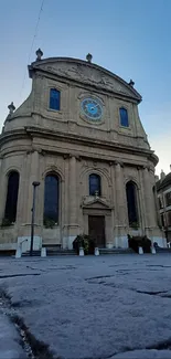 Historic church under a dusky blue sky with stone pavement foreground.