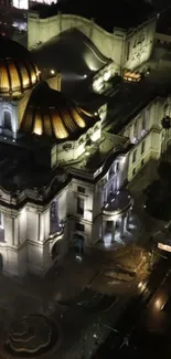 Aerial view of an illuminated historic building at night with glowing architecture.