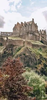 Historic castle on a rocky hill with cloudy sky backdrop.