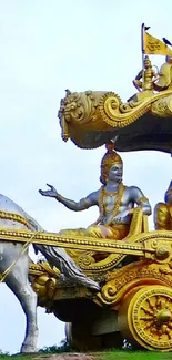 Golden chariot with horses on a green field under a blue sky.