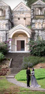 Bride and groom in front of a historic church amidst greenery.