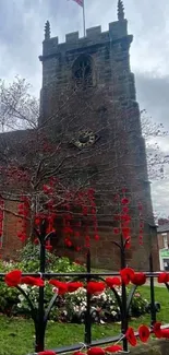 A historic church with red poppies on a grey, cloudy day.