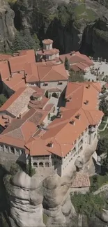 Aerial view of a historic monastery on a cliff under a clear sky.