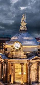 Illuminated historic dome under dramatic sky at night.