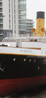 Historic ship docked in urban cityscape with modern buildings.