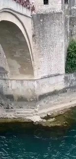 Stone bridge over a teal river with historic charm.