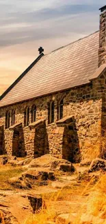 Historic stone church with sunset sky and warm hues.