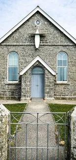 A historic stone church with a gray facade and blue door.