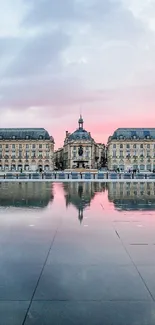 Historic building reflected in water under a pink and blue sunset sky.