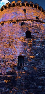 Historic stone tower illuminated under a full moon in a night sky.