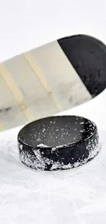 Close-up of a hockey stick and puck on ice.