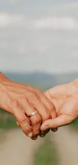 Two hands gently holding each other amidst nature.