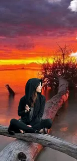 Hooded figure sitting by a vibrant sunset over tranquil waters.