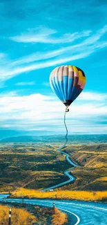 Colorful hot air balloon soaring over a winding road in a vivid landscape.