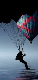 Paraglider and hot air balloon over water at twilight.