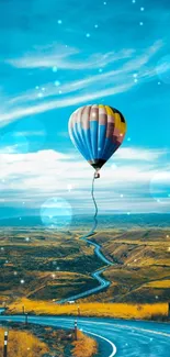 Hot air balloon over a winding countryside road with a vibrant blue sky.