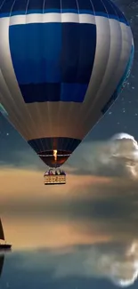 Hot air balloon glides over serene lake at night.