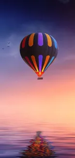 Colorful hot air balloon floating at sunset over calm reflective water.