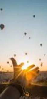 Sunrise with hot air balloons and hand reaching for the sun.