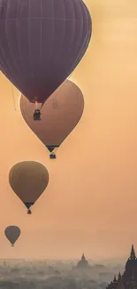 Hot air balloons float over ancient temples at sunrise, creating a serene mobile wallpaper.