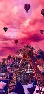 Hot air balloons float beneath a vibrant pink sunset sky.