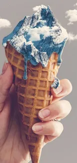 Hand holding an ice cream cone with a mountain.