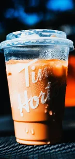 Chilled iced coffee in a plastic cup with vibrant background.