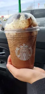 Iced coffee in a car setting with hand holding the cup.