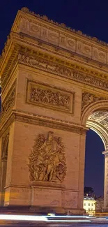 Arc de Triomphe lit up at night, with moving lights below.