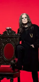 Rock star poses with vintage chair against red background.