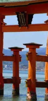 Iconic Torii gate over serene water with mountains in the background.