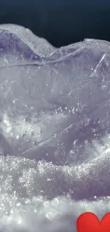 Heart-shaped ice with red heart on snow.