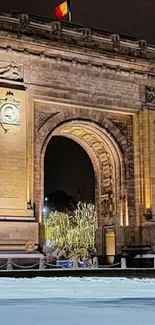 Illuminated arch monument on a snowy night.