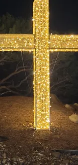 A glowing cross illuminated at night in a peaceful natural setting.