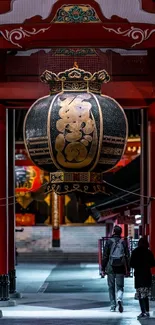 Illuminated pathway of a Japanese temple with vibrant reds and glowing lantern.