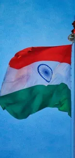 Indian flag waving in blue sky on a tall pole.